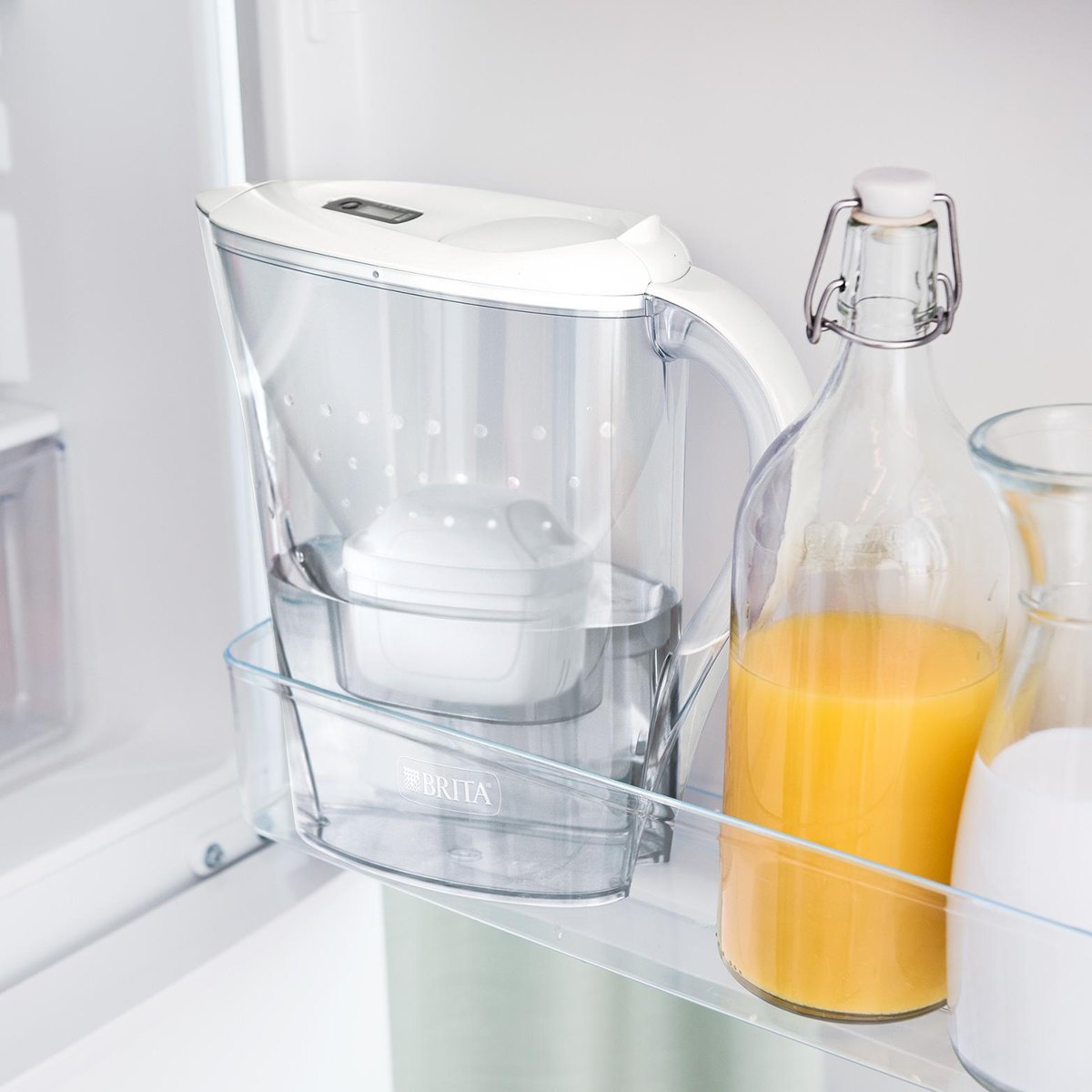 Caraffa BRITA Marella inserita nella porta di un frigorifero accanto a una bottiglia