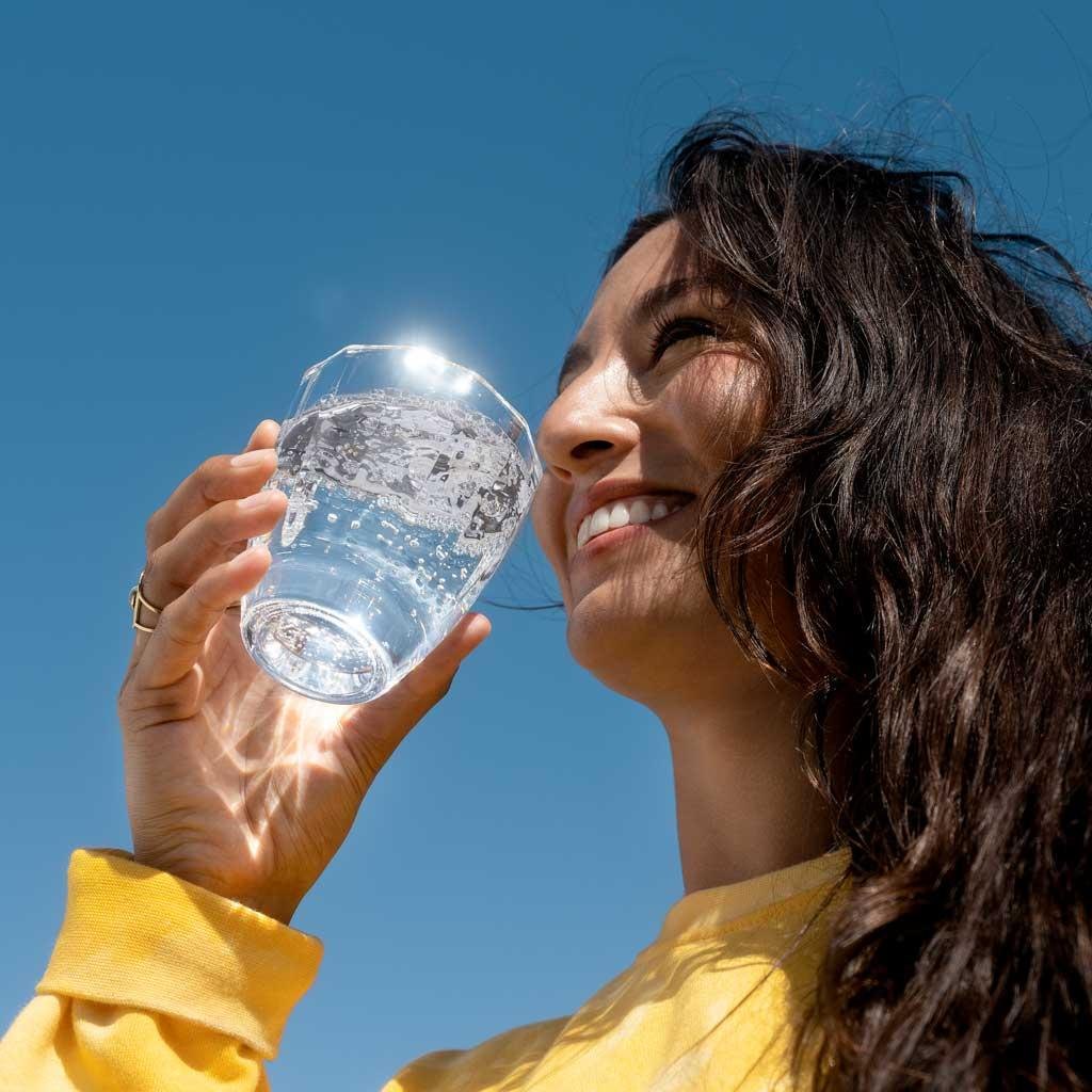 Persona che beve un bicchiere d’acqua all’aperto